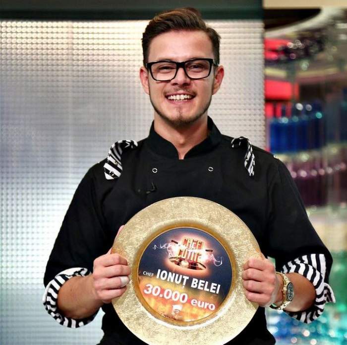 Ionuț Belei se află la Chefi la Cuțite. Tânărul poartă uniformă neagră de bucătar și ține în mâini marele premiu de 30.000 de euro.