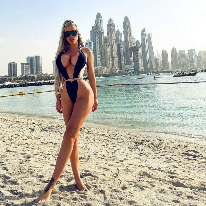 Loredana Chivu se ală pe o plajă din Dubai. Vedeta poartă un costum negru, având decolteul și zona intimă la vedere. Diva are gura întredeschisă.