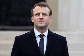 Emmanuel Macron, zâmbitor, în costum negru