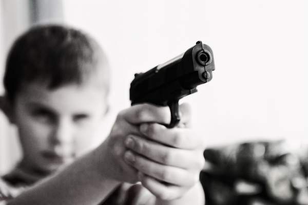 Un copil cu un pistol în mână