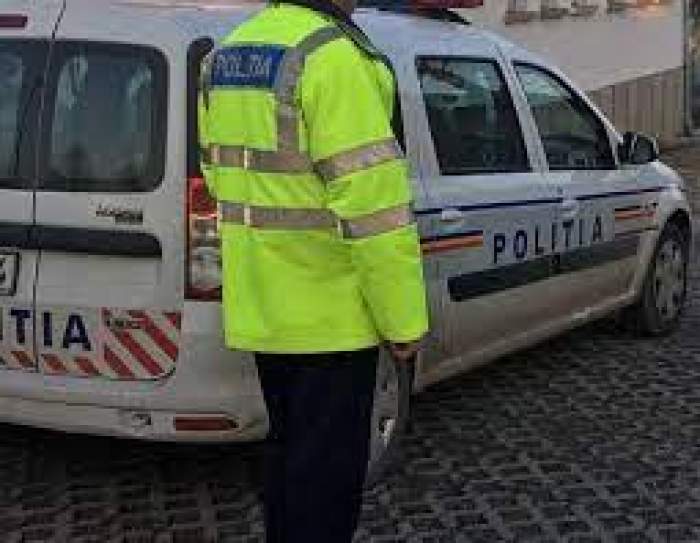 Un polițist în uniformă lângă mașina de lucru