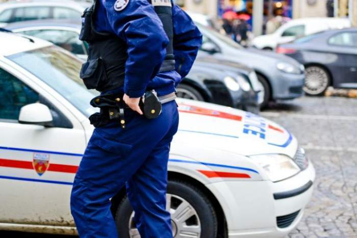 Un polițist în uniformă lângă mașina de lucru