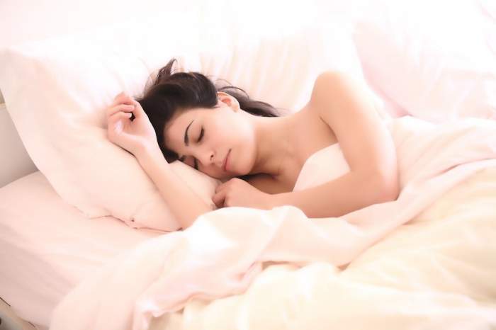 O femei care doarme într-un pat alb