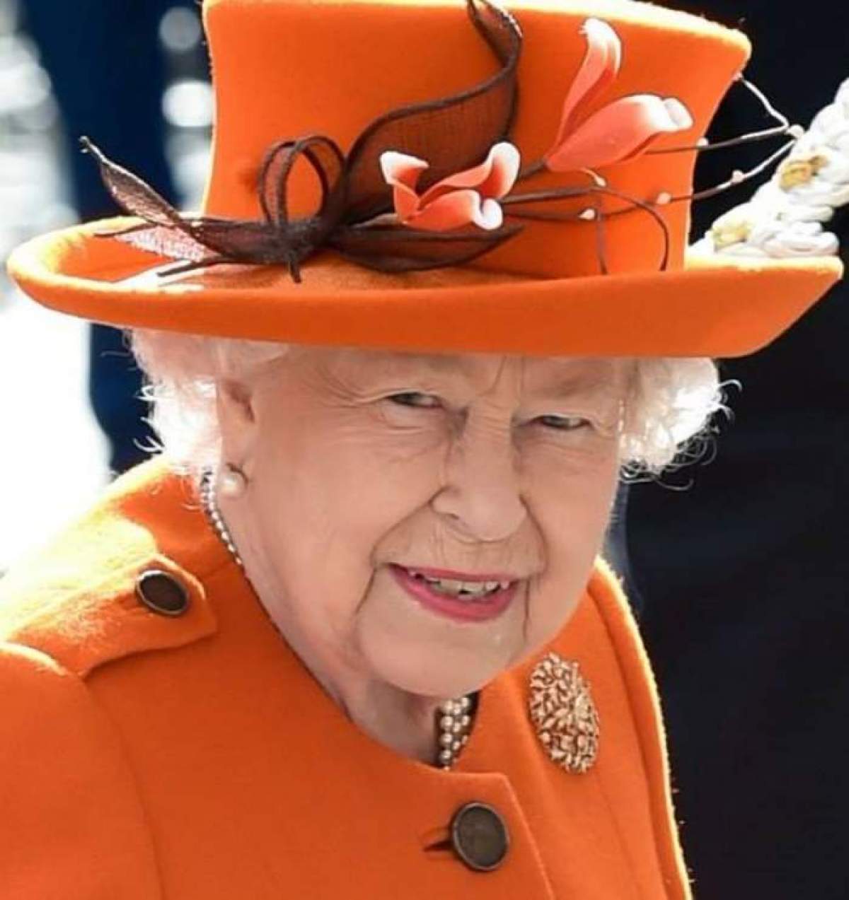 Regina Elisabeta a II-a, îmbrăcată în portocaliu, la un eveniment public