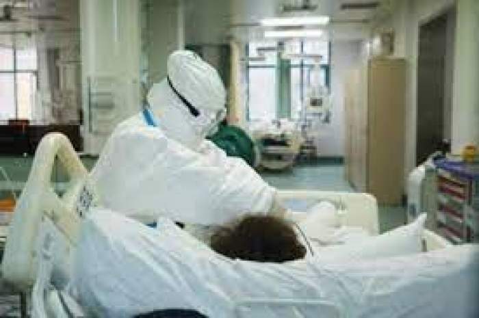 Medic în combinezon și un pacient întins pe pat