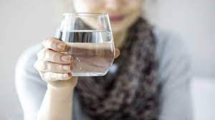 O femeie care ține un pahar de apă în mână
