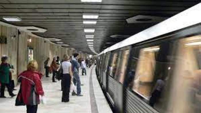 Oameni pe peronul metroului aflat în stație
