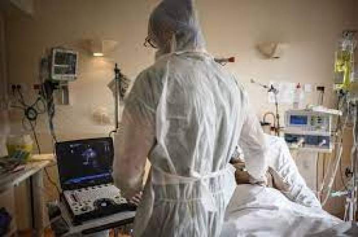 Un medic în combinezon verifică un pacient intubat