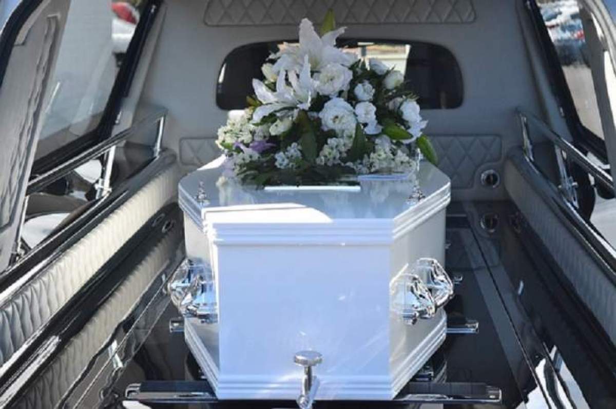 Un sicriu alb cu flori pe el, în mașină