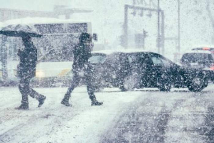 oameni care trec starda în timp ce ninge