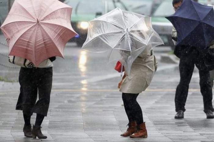 Femei pe stradă, cu umbrelele luate de vânt