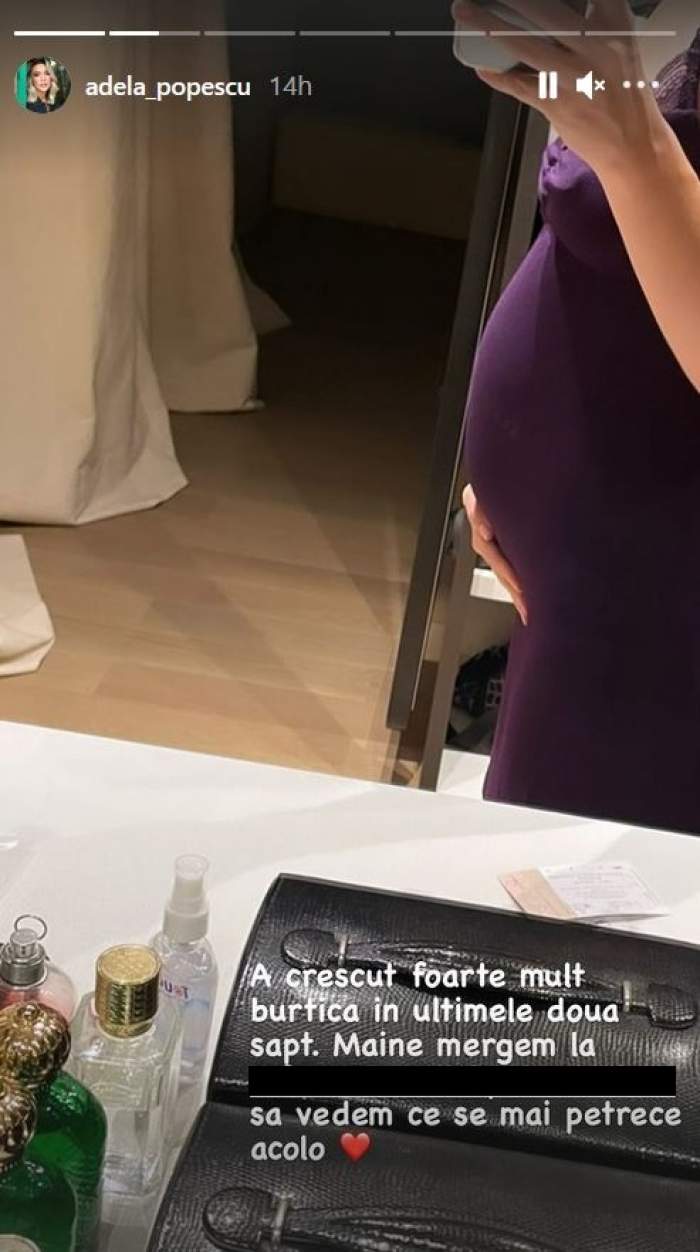 Adela Popescu poartă o rochie mov. Artista își ține o mână pe burtica de gravidă și se fotografiază cu telefonul în oglindă.