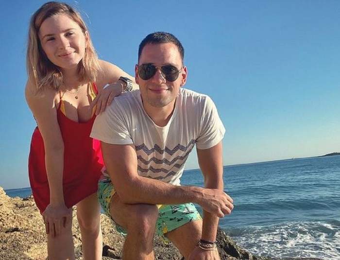 Cristina Ciobănașu și Vlad Gherman sunt la mare. Ea poartă o rochie roșie, iar el un tricou alb cu model cu linii în zig-zag și niște pantaloni scurți verzi cu model cu bărci.