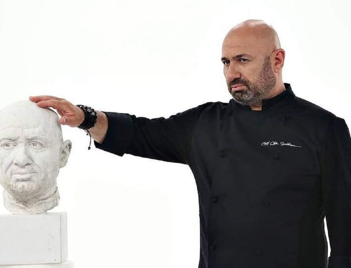 Cu cine a petrecut Cătălin Scărlătescu pe 14 februarie Cătălin Scărlătescu poartă o uniformă neagră de bucătar. Chef-ul ține mâna pe o statuie cu chipul său.