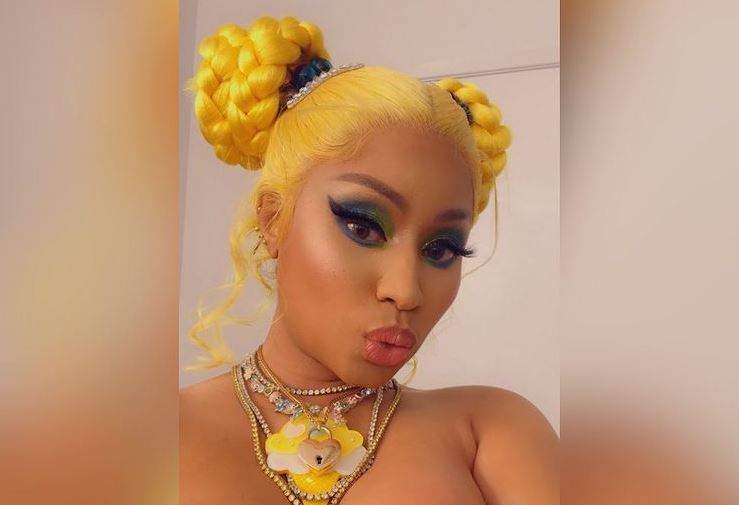 Nicki Minaj poartă o perucă blondă și o ține prinsă în coc. Vedeta are la gât un colier galben.