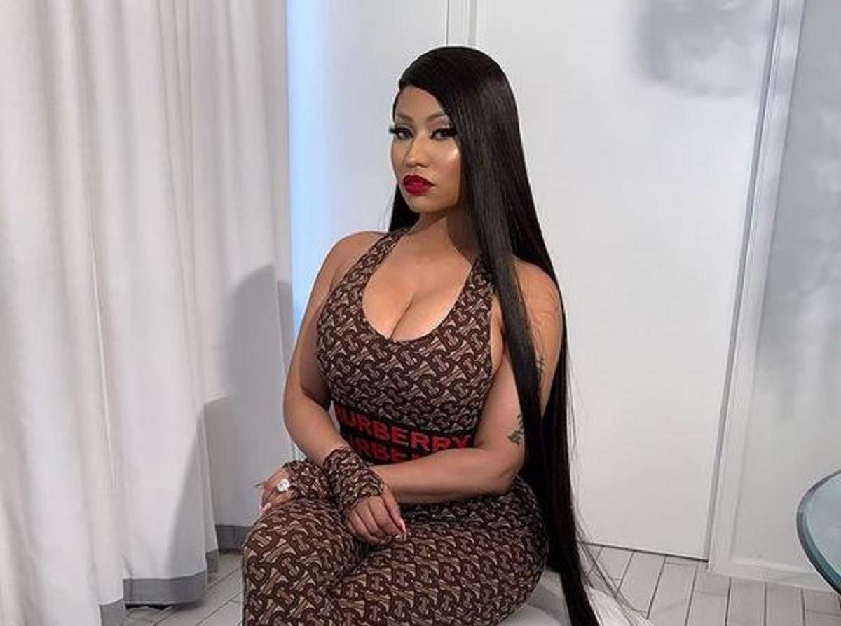 Nicki Minaj stă pe un scaun. Vedeta poartă o salopetă maro.