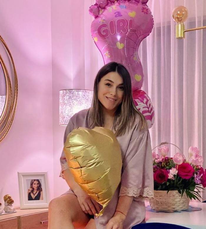 Monica Rosu poarta un halat din satin roz, sta in camera copilului si tine un balon auriu in mana