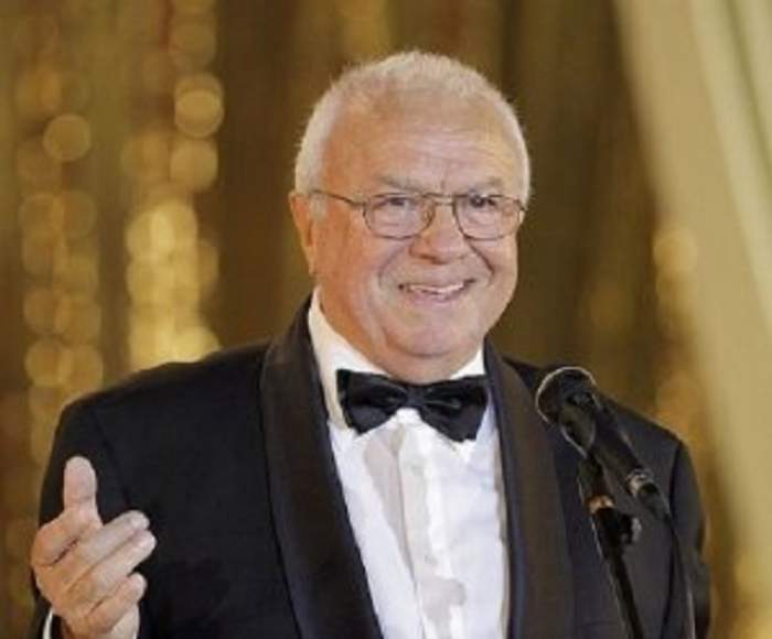 Alexandru Arșinel la costum, gesticulând, fiind zâmbitor