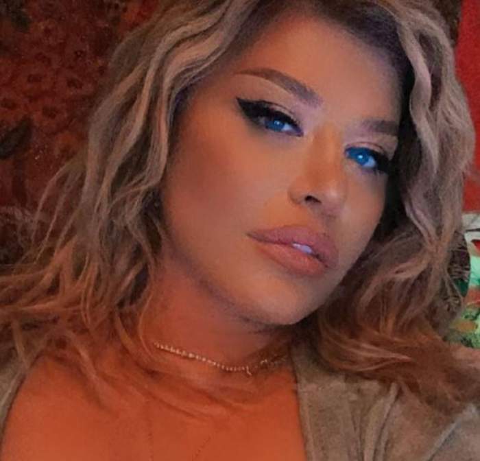Loredana Groza își face un selfie. Vedeta e în pat, poartă un tricou gri și are gura întredeschisă.