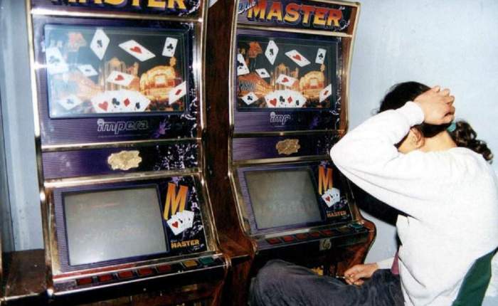 O persoană supărată stă în fața a două aparate de jocuri de noroc