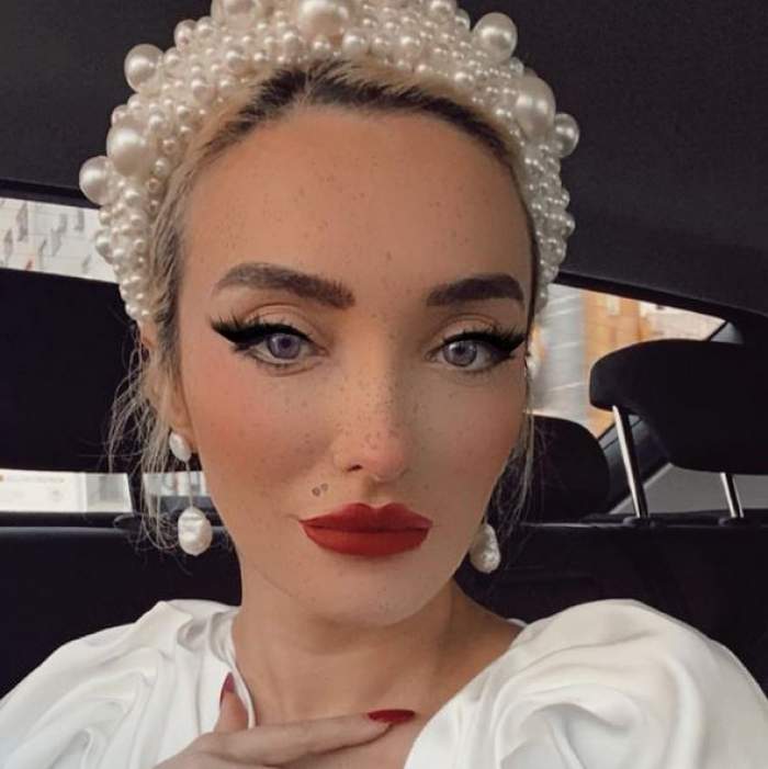 Ana Morodan își face selfie în mașină. Vedeta poartă o bluză albă și bentiță și cercei cu perle.
