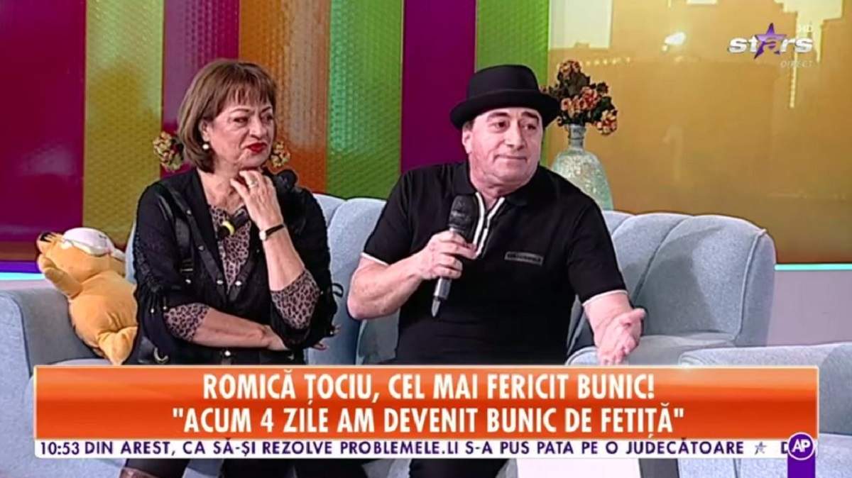 Cum a reacționat Romică Țociu când și-a cunoscut nepoțica Romică Țociu și Adriana Trandafir se află pe canapeaua gri de la Star Matinal. El poartă pălărie și tricou negru, iar ea o bluză cu animal print și o alta neagră descheiată pe deasupra.