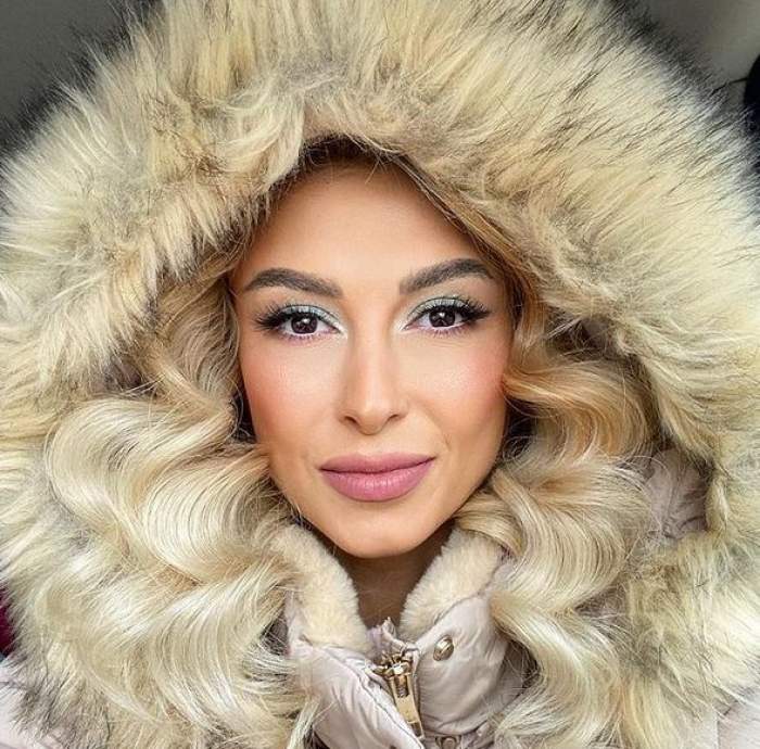 Andreea Bălan este îmbrăcată într-o geacă de iarnă crem. Artista zâmbește și își face un selfie.
