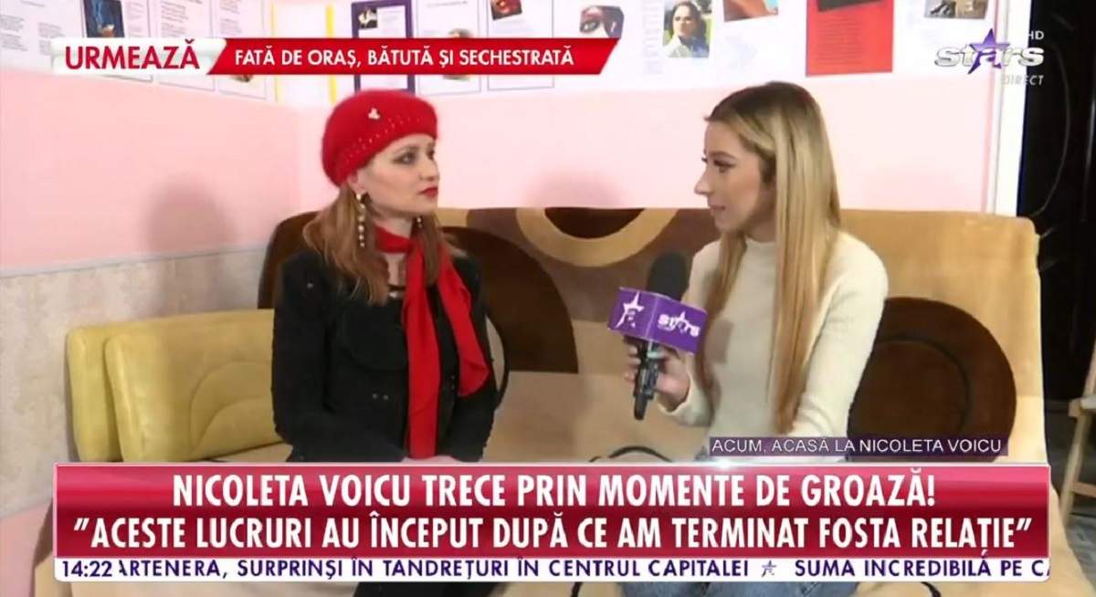 Nicoleta Voicu dă un interviu pentru Antena Stars. Vedeta stă pe o canapea maro și e îmbrăcată cu o bluză neagră. Artista poartă o căciulă și eșarfă roșie.