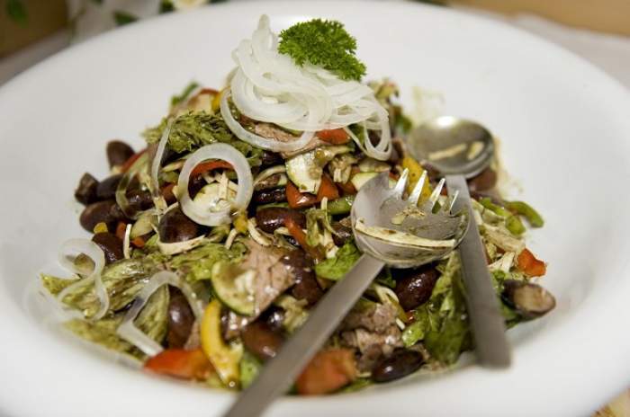 Salata pusă într-o farfurie albă, cu o furculiță peste
