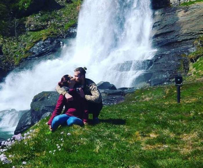 Silviu Costan și soția lui se află pe iarbă, în fața unei cascade. Cei doi se sărută cu foc. Fostul concurent de la Chefi la cuțite are părul prins în coadă.