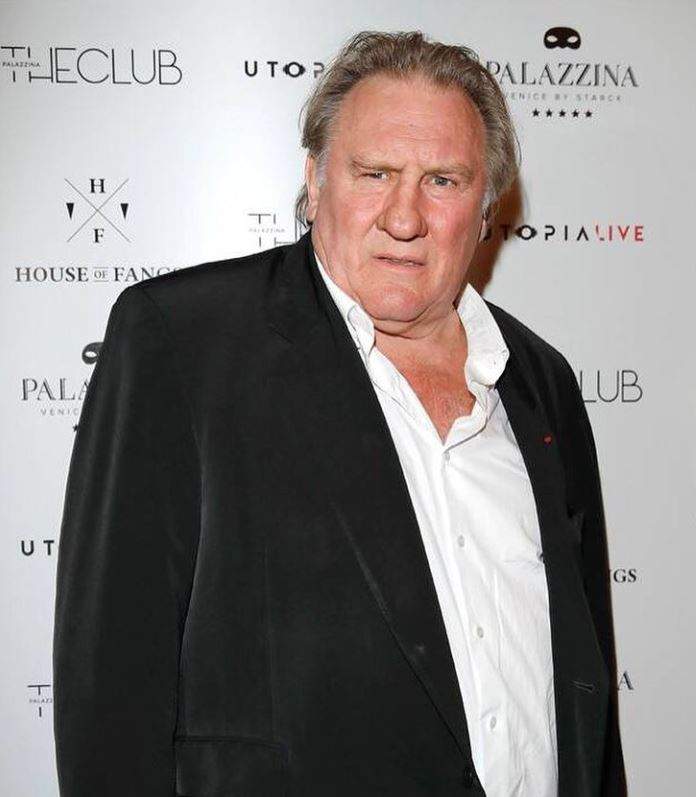 Gerard Depardieu este pe covorul rosu la un eveniment, poarta costum negru cu camasa alba descheiata