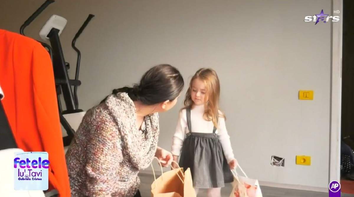 Gabriela Cristea și fiica ei cea mare, Iris, împachetează mai multe produse într-o pungă de hârtie. Vedeta poartă un pulover colorat, iar micuța o rochie gri.