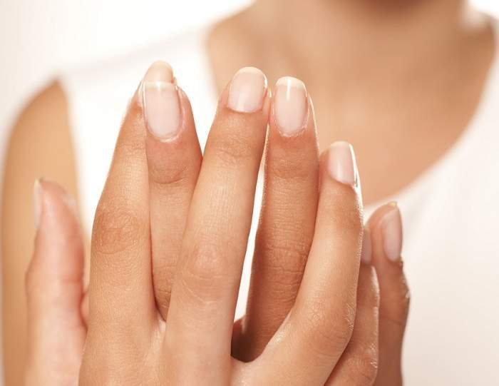 O femeie își arată unghiile perfecte, încrucișându-și mâinile