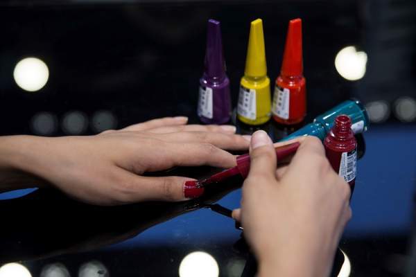 O femeie își face unghii cu culori diferite