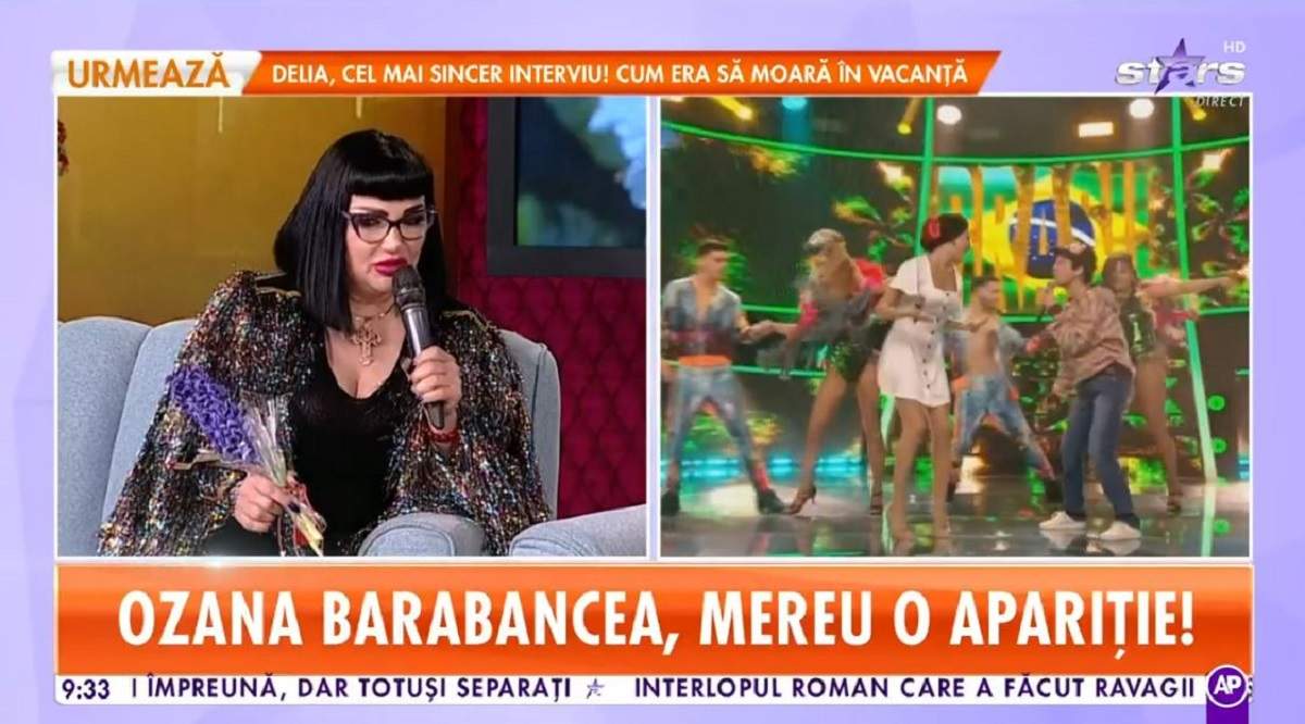 Ozana Barabancea stă pe canapeaua bleu de la Star Matinal. Vedeta ține microfonul și o zambilă mov în mână și poartă o bluză neagră, iar pe deasupra un sacou cu paiete colorate.