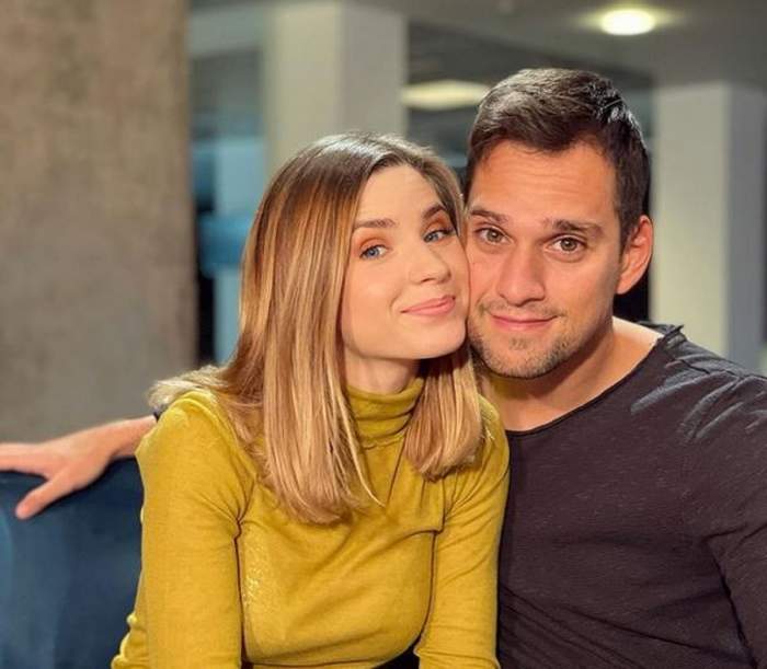 Cristina Ciobănașu și Vlad Gherman pe vremea când erau împreună. Stau pe o canapea albastră. El poartă o bluză gri închis, iar ea o maletă galbenă.