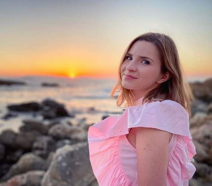 Cristina Ciobănașu se află la mare. Artista poartă o rochie roz și zâmbește.