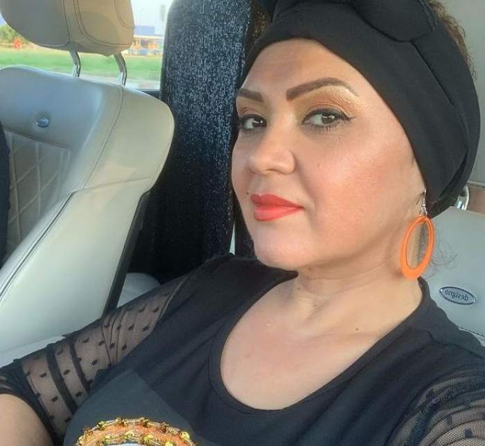 Minodora poartă un turban negru pe cap și cercei rotunzi, oranj, la ureche. Vedeta se află în mașină și e îmbrăcată cu o bluză neagră.