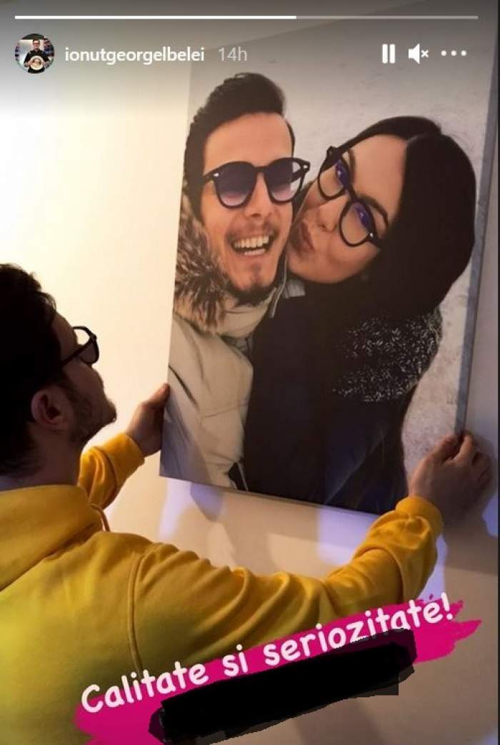 Ionuț Belei le-a arătat fanilor de pe Instagram că i-a cumpărat iubitei un tablou cu ei doi. Tânărul poartă un hanorac galben și pune tabloul pe peretele alb.
