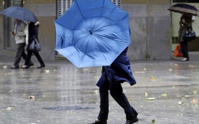 oameni cu umbrela in ploaie
