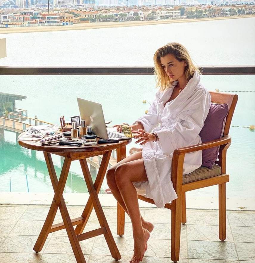 Denisa Tănase, în halap alb, pe balcon, lucrează la laptop
