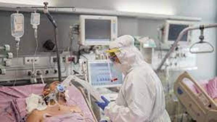 Medic în combinezon și un pacient pus la aparate