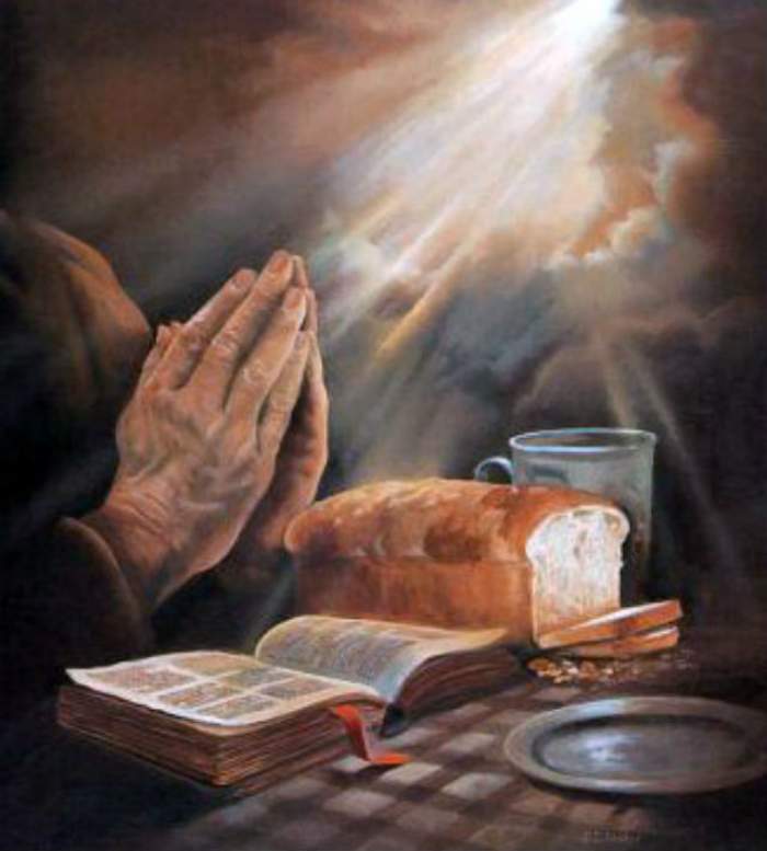 O persoană care se roagă, o carte de rugăciuni și o pâine