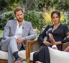 Prințul Harry și Meghan Markle, îmbrăcați în gri și negru, în cadrul unui interviu