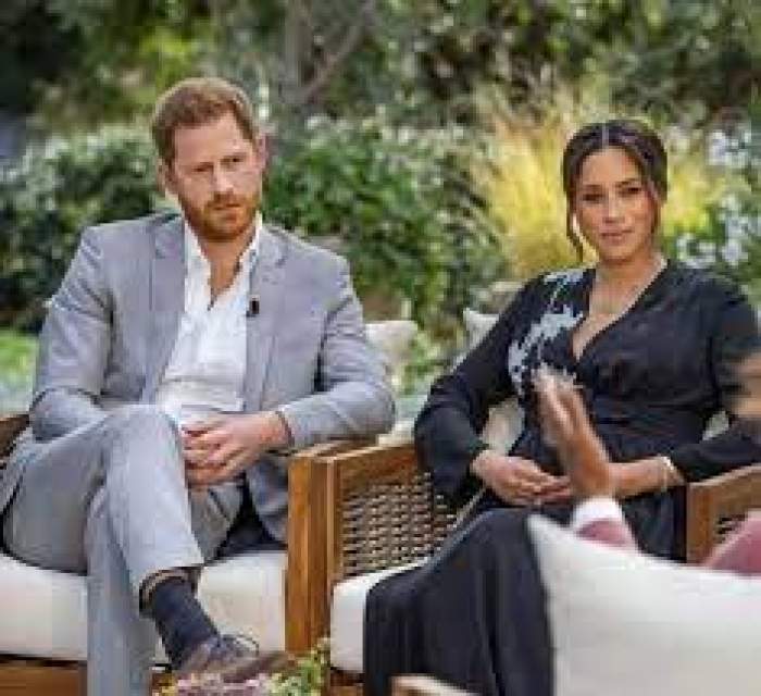 Prințul Harry și Meghan Markle, îmbrăcați în gri și negru, în cadrul unui interviu