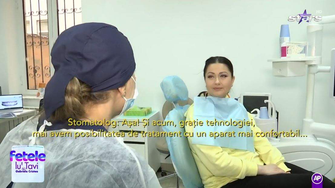 Gabriela Cristea se află la dentist. Vedeta poartă o bluză galbenă și discută cu stomatologul.