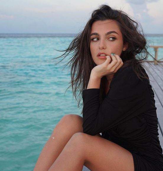 Alexia Eram e în Maldive. Artista poartă o rochie neagră și privește într-o parte susținându-și bărbia în palmă.