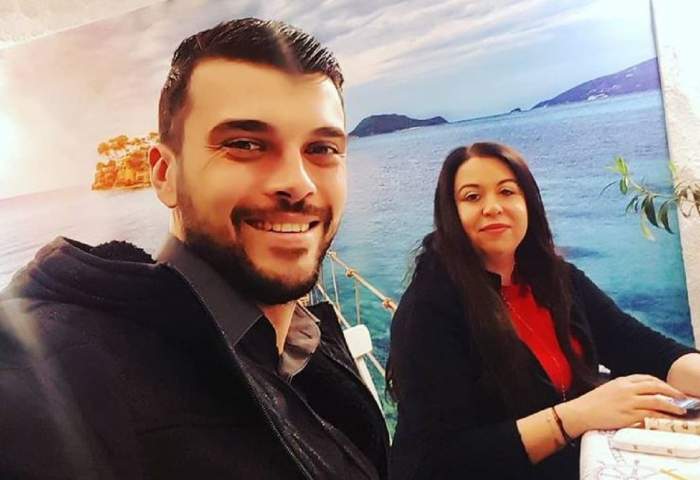 Oana Roman și Marius Elisei se află la un restaurant. Ea poartă o bluză roșie cu o geacă neagră pe deasupra, iar el o cămașă și o haină neagră.