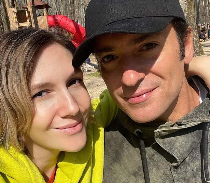 Adela Popescu și Radu Vâlcan sunt în parc. Artista poartă un hanorac galben, iar soțul ei unul gri și o șapcă neagră. Amândoi zâmbesc.