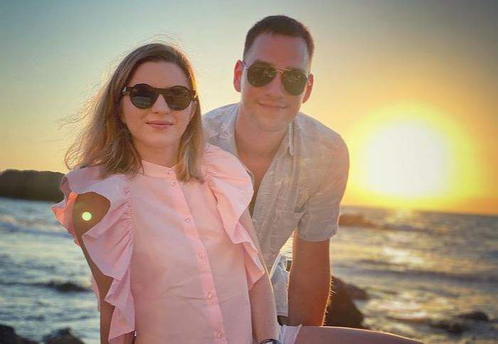Vlad Gherman și Cristina Ciobănașu sunt la mare. Amândoi poartă ochelari de soare. Ea poartă o cămașă roz, cu mânecă scurtă, iar el una albă spre bleu.
